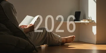 Person reading book in minimalist room, phone on shelf, symbolizing digital minimalism and focus.