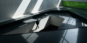 A person walking on a geometric concrete and granite pathway under harsh overhead light, symbolizing the dynamic, multi-faceted nature of modern career paths and the future of work.