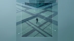 Unveiling Tomorrow: Predictions for Digital Lifestyles, Security, and the Evolving Workplace Aerial view of a person walking on a geometrically patterned urban plaza at dawn, symbolizing ambient computing and integrated digital living.